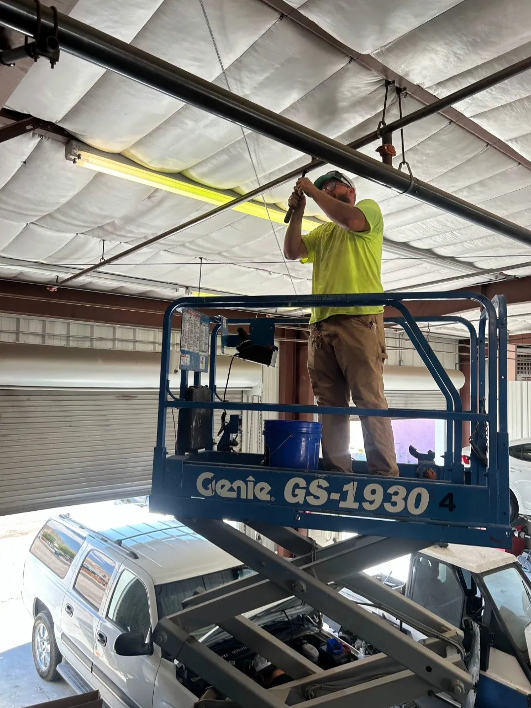 A Craig Fire Protection technician on a scissor lift working on overhead piping inside a shop building