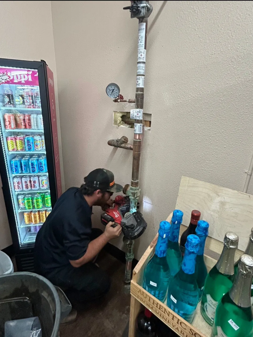 A Craig Fire Protection technician working at a water riser with a pressure gauge inside a retail store